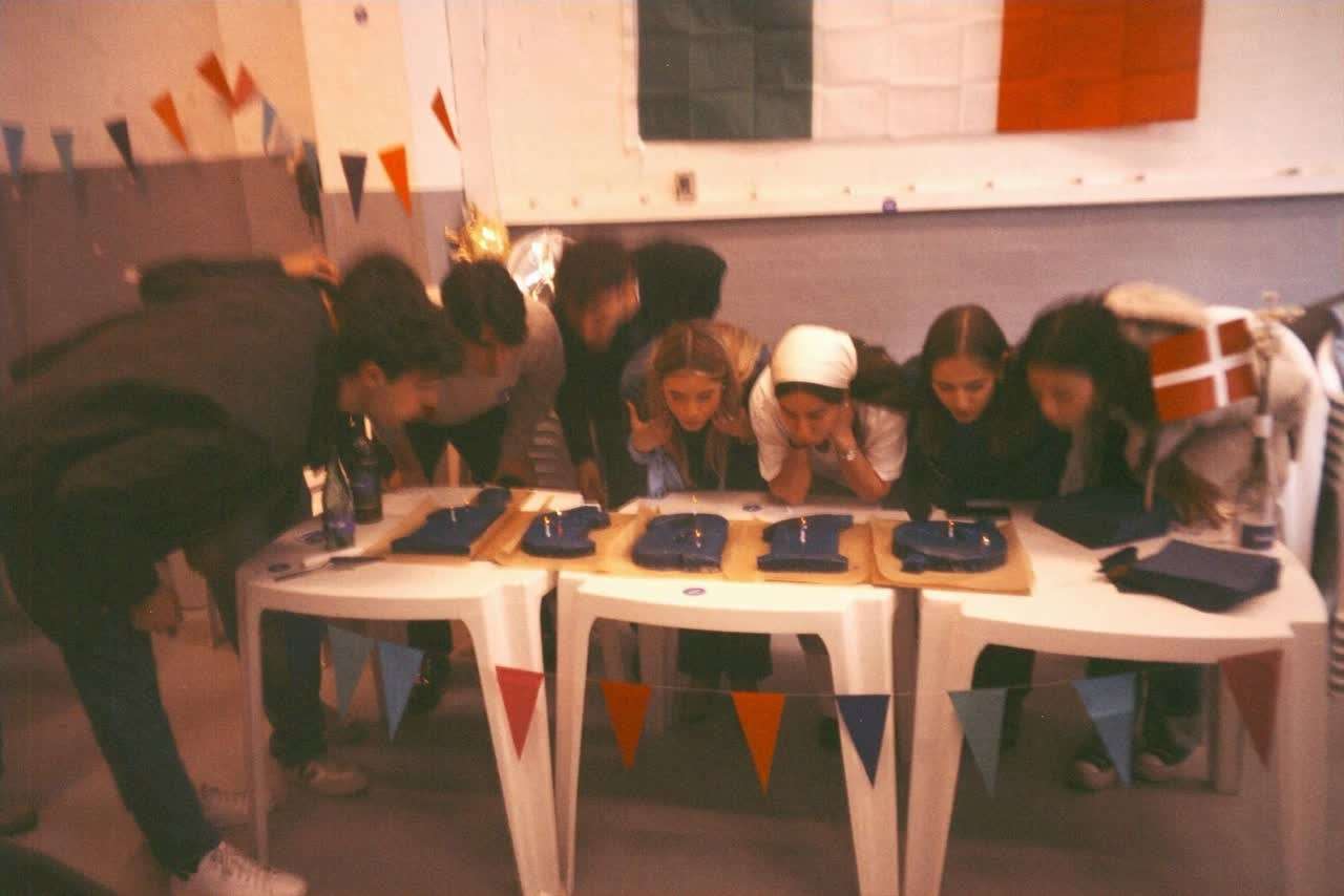 Guests leaning over tables during a tasting game, Italian flag and bunting on the wall