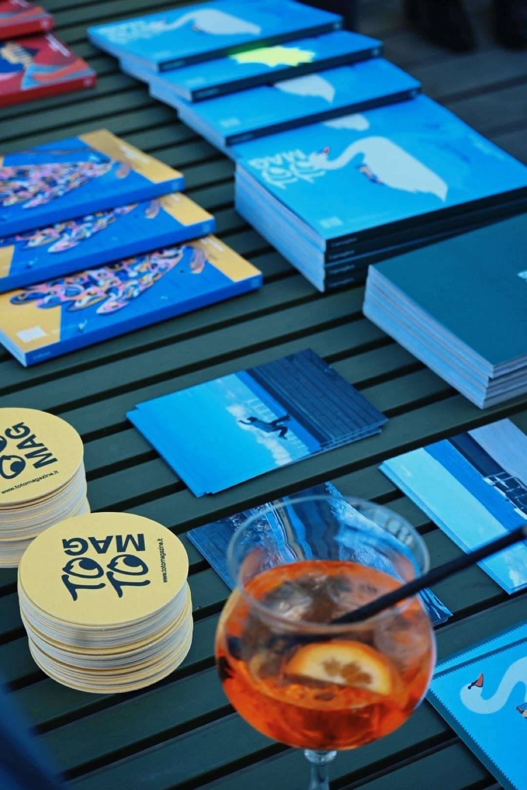 Copies of TO TO MAG on a table with branded coasters and a spritz