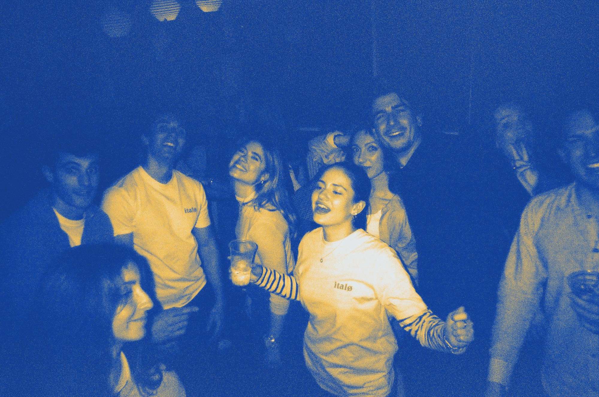 italø members dancing and laughing at a party, in the blue and yellow duotone italø uses on its own site